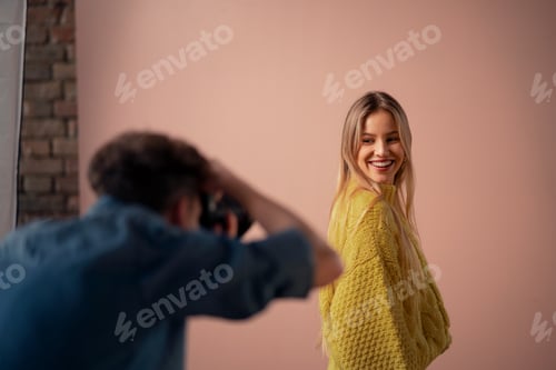 Visualização: Jovem fotógrafo tirando fotos da modelo, nos bastidores da sessão de fotos em estúdio.