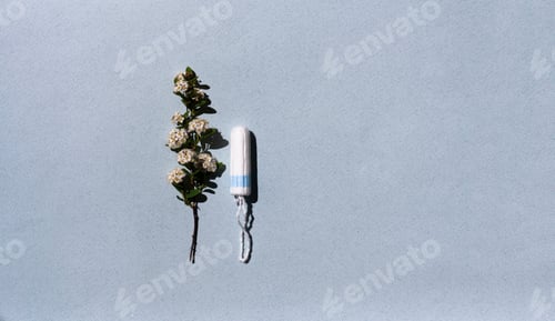 Preview: Medical female tampon and white flowers on a blue background.