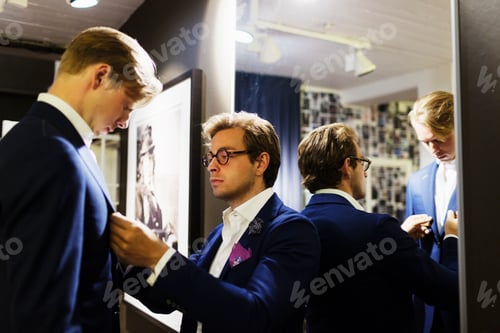Preview: Salesman fitting suit on customer at clothing store