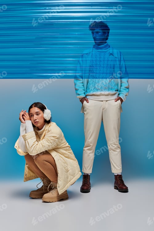 Preview: asian woman in earmuffs sitting on haunches near man behind blue plastic sheet, winter fashion