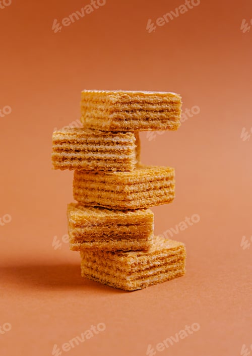 Preview: Stack of crispy wafers on a warm orange background creating a visually pleasing dessert display