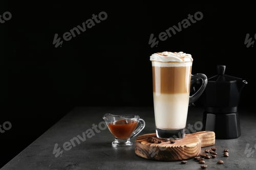 Preview: Glass cup of caramel macchiato and gravy boat with syrup on table, space for text
