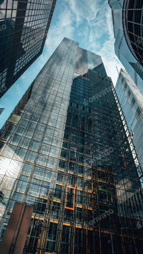 Preview: Low-angle view of modern skyscrapers with reflective glass facades.
