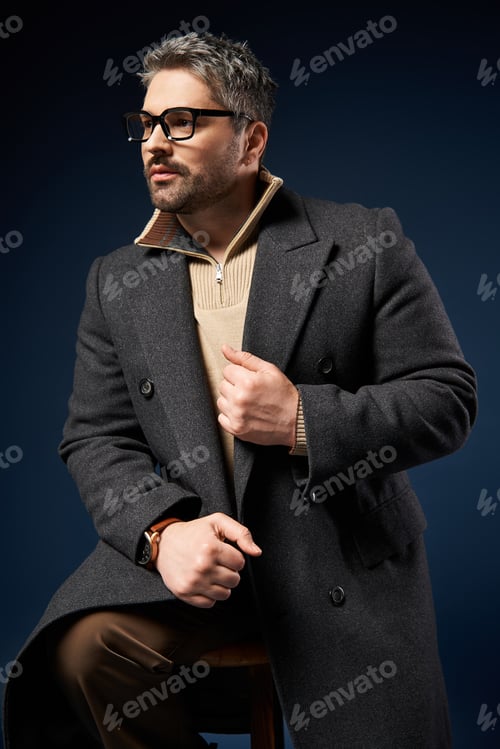Preview: Handsome man in trendy glasses showcases elegant style in fashion studio setting
