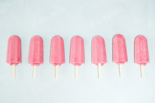 Preview: Strawberry flavored pink popsicles in the row flat lay on the white background.