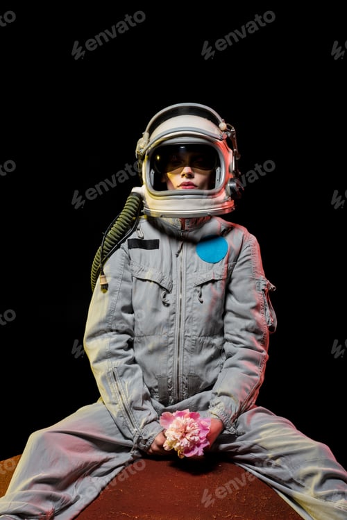 Preview: female astronaut in spacesuit and helmet sitting on planet with flower in cosmos