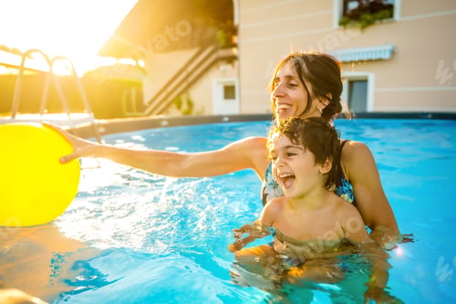 Preview: Mother and son playing with inflatable ball in swimming pool during summer vacation