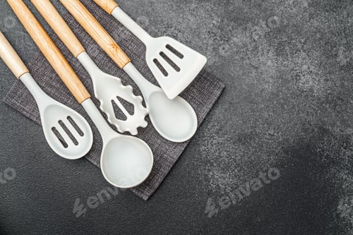 Preview: Cooking tools arranged on dark surface with textured fabric underneath