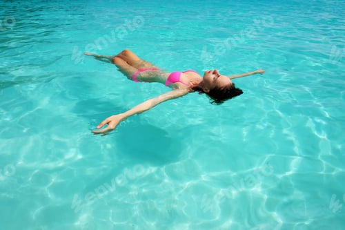 Preview: Woman In Bikini Lying On Water At Tropical Beach