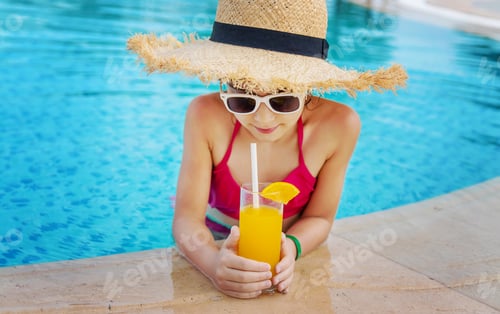 Preview: The child is drinking a cocktail by the pool. Selective focus.