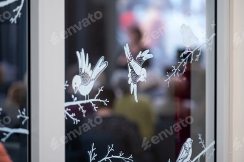 Preview: Bird decorations on glass window at a cozy indoor setting during a gathering