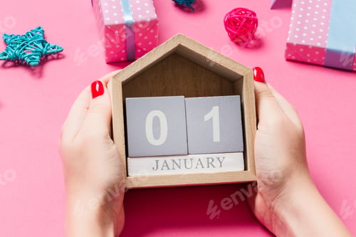 Preview: Top view of female hands holding calendar on pink background