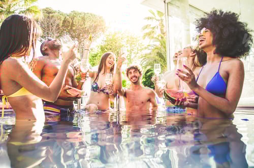 Preview: Multi-ethnic group of friends toasting champagne on a pool party