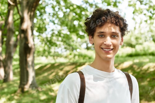 Preview: Young man enjoys a sunny day in a vibrant green park wearing a casual white t-shirt
