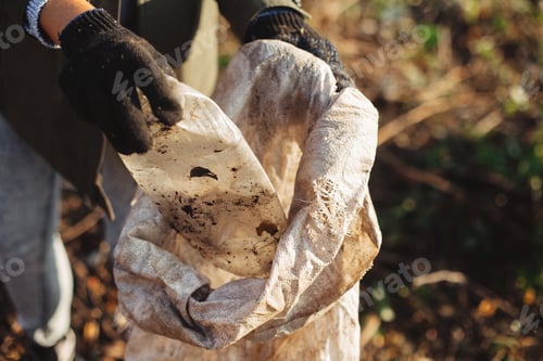 Preview: Woman hand in glove picking up trash, collecting garbage in bag