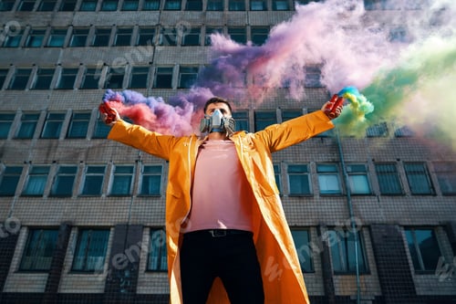 Preview: Young man in respirator mask hold smoke bombs in raised hands