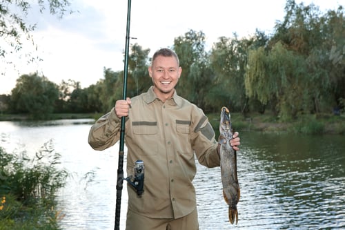 Preview: Man with rod and catch fishing at riverside. Recreational activity