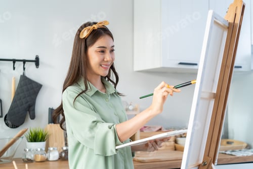 Preview: Asian young talented woman artist coloring on painting board in house.