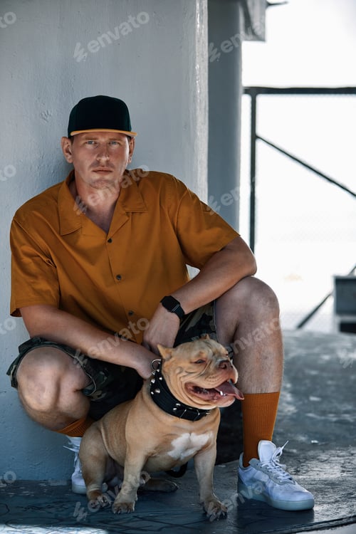 Preview: young stylishly dressed man with american bully dog on city streets