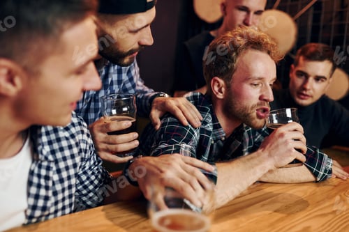 Preview: Sad man feels bad. Group of people together indoors in the pub have fun at weekend time