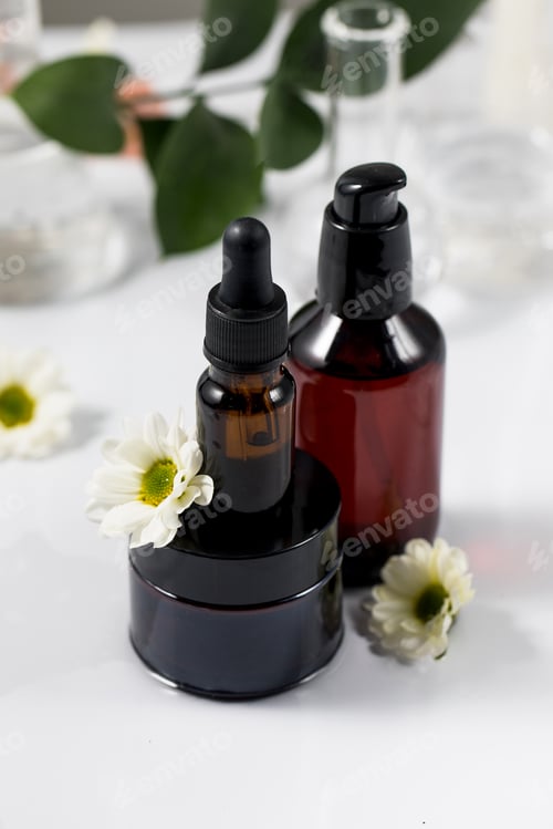 Preview: Organic cosmetics stands on the water, next to white flowers and a plant.