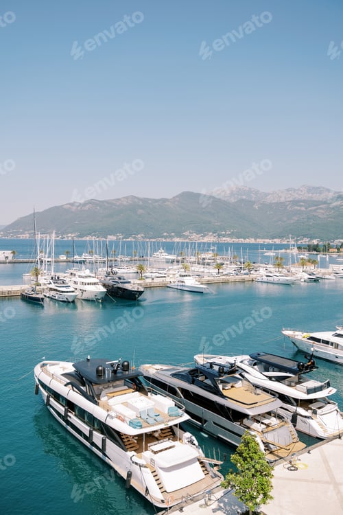 Preview: Row of double-decker yachts with sun loungers on the roof are moored at the pier of a luxury marina