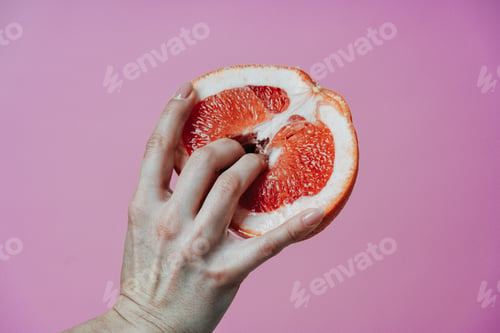 Vorschau: Bild einer weiblichen Hand mit Finger in einer frischen Grapefruit