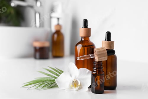 Preview: Essential oils and orchid flower on white table in bathroom, closeup