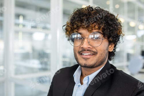 Preview: Confident young businessman smiling in modern office