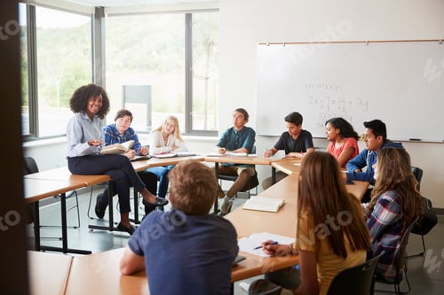 Preview: Female High School Tutor Sitting At Table With Pupils Teaching Maths Class