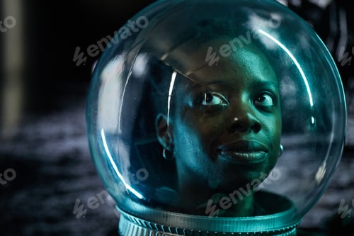 Preview: Portrait of Young Adult Black Woman Wearing Astronaut Helmet Gazing Upward