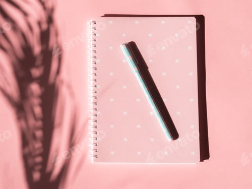 Preview: Pink notebook with pen and tropical plant shadow