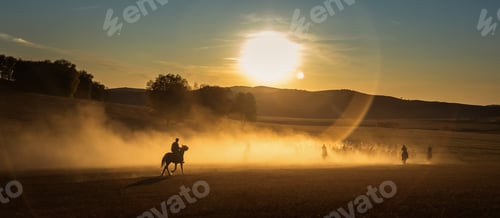 Preview: Group of people riding horses on a picturesque trail at sunset.