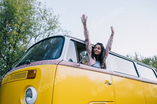 Preview: happy attractive female traveler in retro minivan