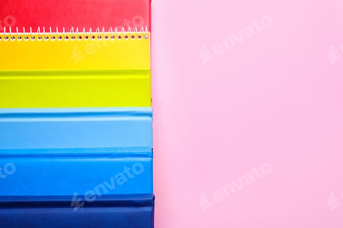 Preview: Bright notebooks and space for text on pink background, flat lay. Rainbow colors
