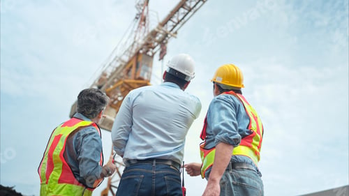 Preview: Group of workers at construction site are discussing construction progress with a tower crane