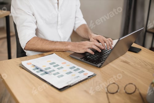 Preview: Close up of male hand in formal wear typing on modern laptop while sitting at desk.