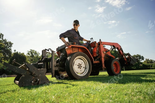 Preview: Loan work. Man is with utility tractor with grass cutter and aerator equipment on the field