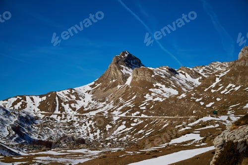 Preview: View of a snow-capped mountain under a clear blue sky in a rugged landscape