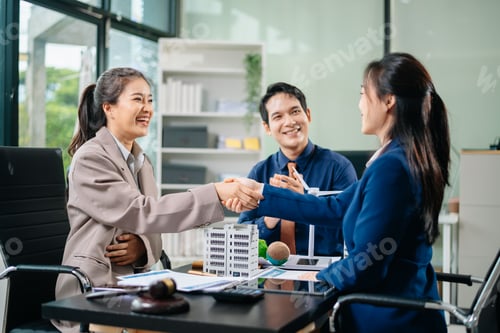 Preview: Two businesswomen shake hands after successful eco-friendly deal as colleague applauds. Great for