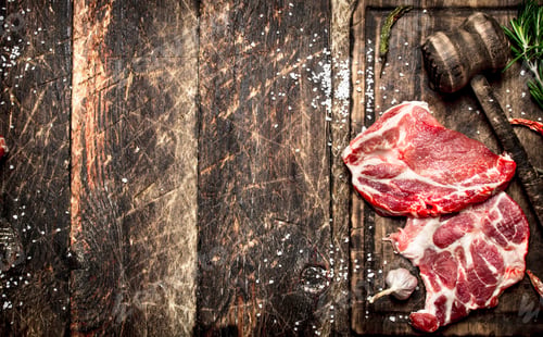 Preview: Raw meat background. Pieces of raw steak with spices and herbs. On wooden background.