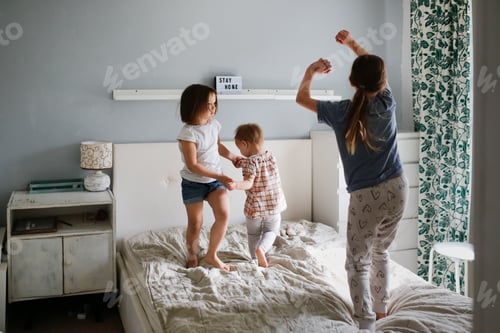 Vista previa: Divertido y loco Tres niños saltan sobre una cama grande en el dormitorio, niños en casa