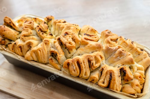 Preview: Homemade rectangular bread with garlic butter and herbs, in a baking tin.
