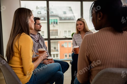 Preview: Diverse group of people sitting in circle in group therapy session.