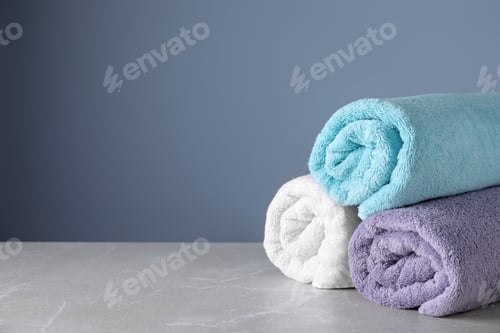 Preview: Fresh rolled bath towels on grey table. Space for text