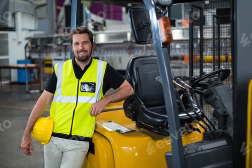 Preview: Portrait of smiling factory worker leaning on forklift