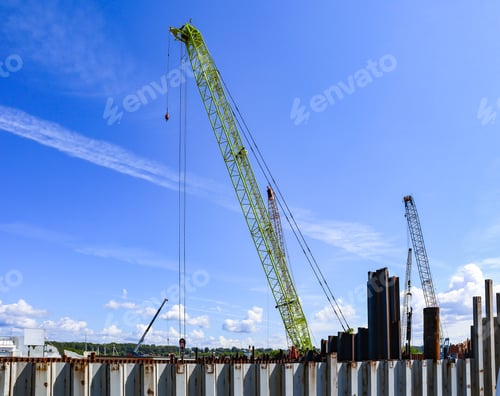 Preview: Port industrial cranes on the river and unloading warehouse on a clear sunny day