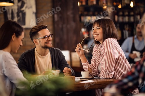Preview: Happy woman talking to her friends while drinking coffee in a cafe.
