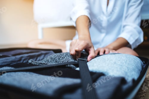 Preview: Closeup image of a woman packing luggage for a trip