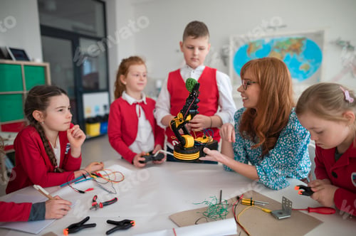 Preview: Group of kids with young science teacher programming electric toys and robots at robotics classroom